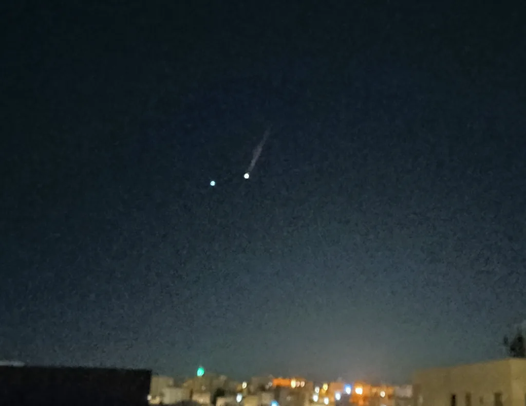 2025年6月、夜の市街地の上空を、尾を引いて飛ぶ2発の弾道ミサイルの光。イランからイスラエルへ向かう弾道ミサイルをヨルダン上空から撮影したもの