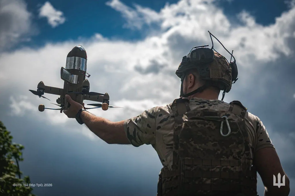 ウクライナ軍の兵士が、迎撃用の小型ドローンを空へ放とうとしている場面。曇り空を背に機体を高く掲げている